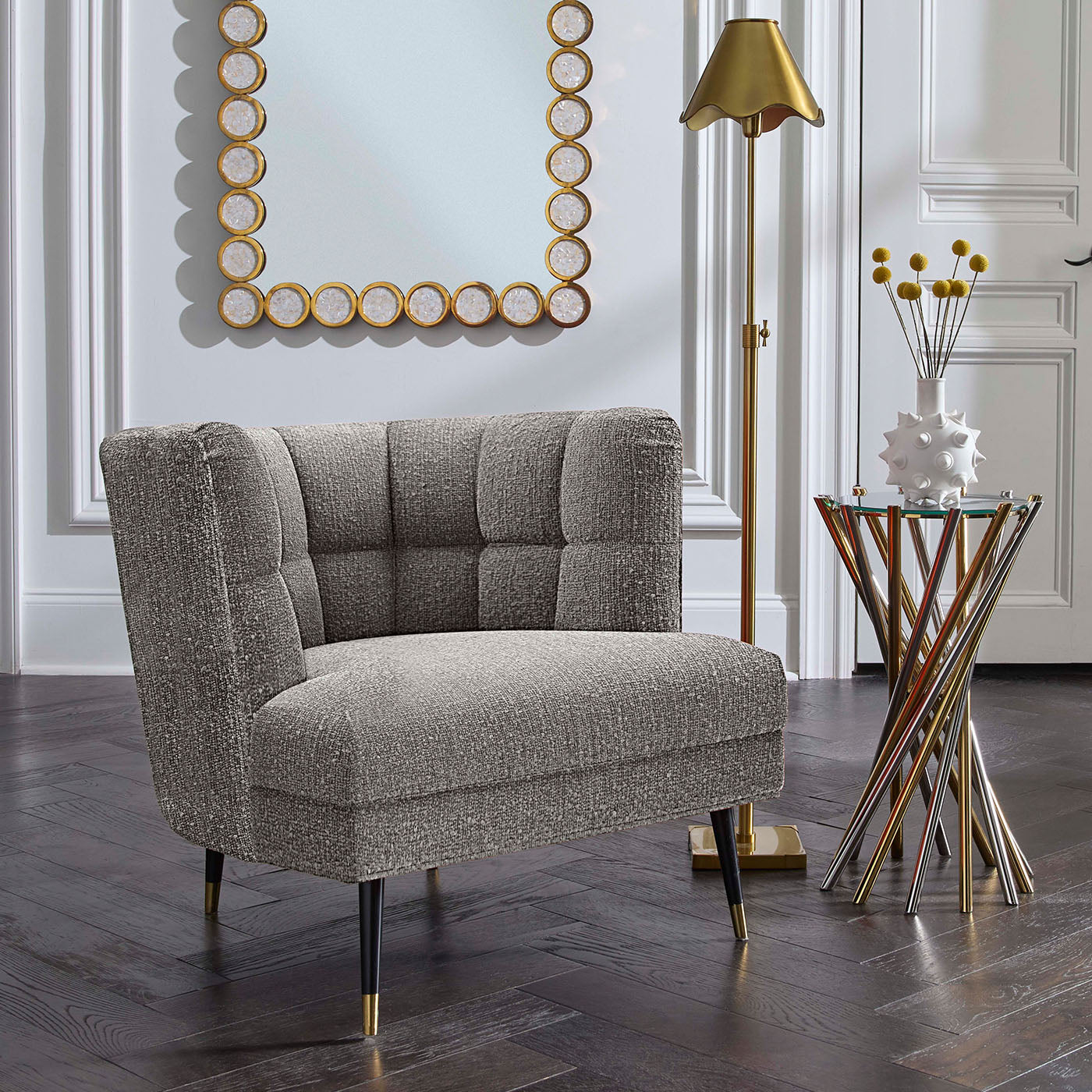 Gray upholstered chair in a stylish room with a mirror and lamp.
