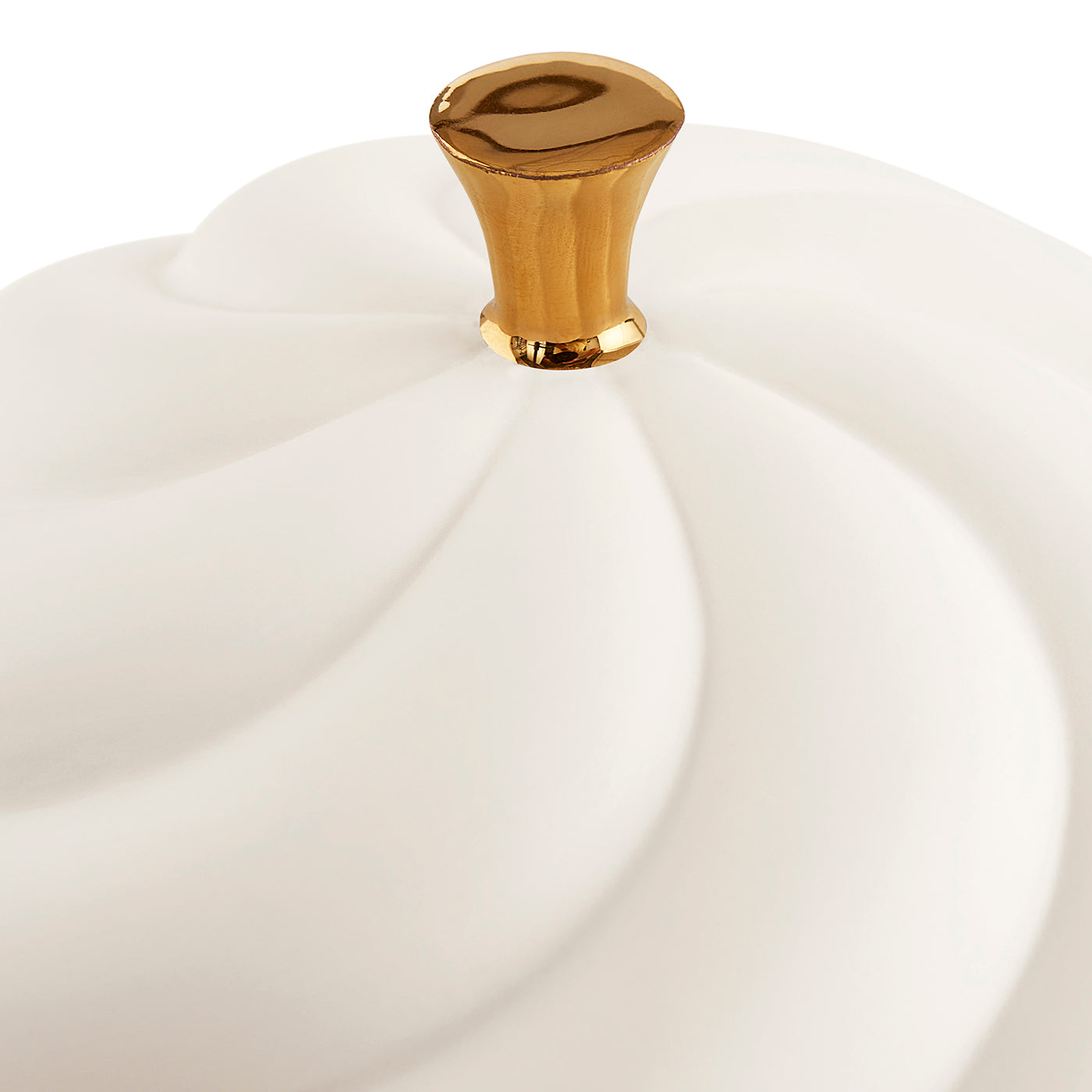 A close-up of a white ceramic container lid with a sculpted, swirled design and a polished gold knob on a white background.