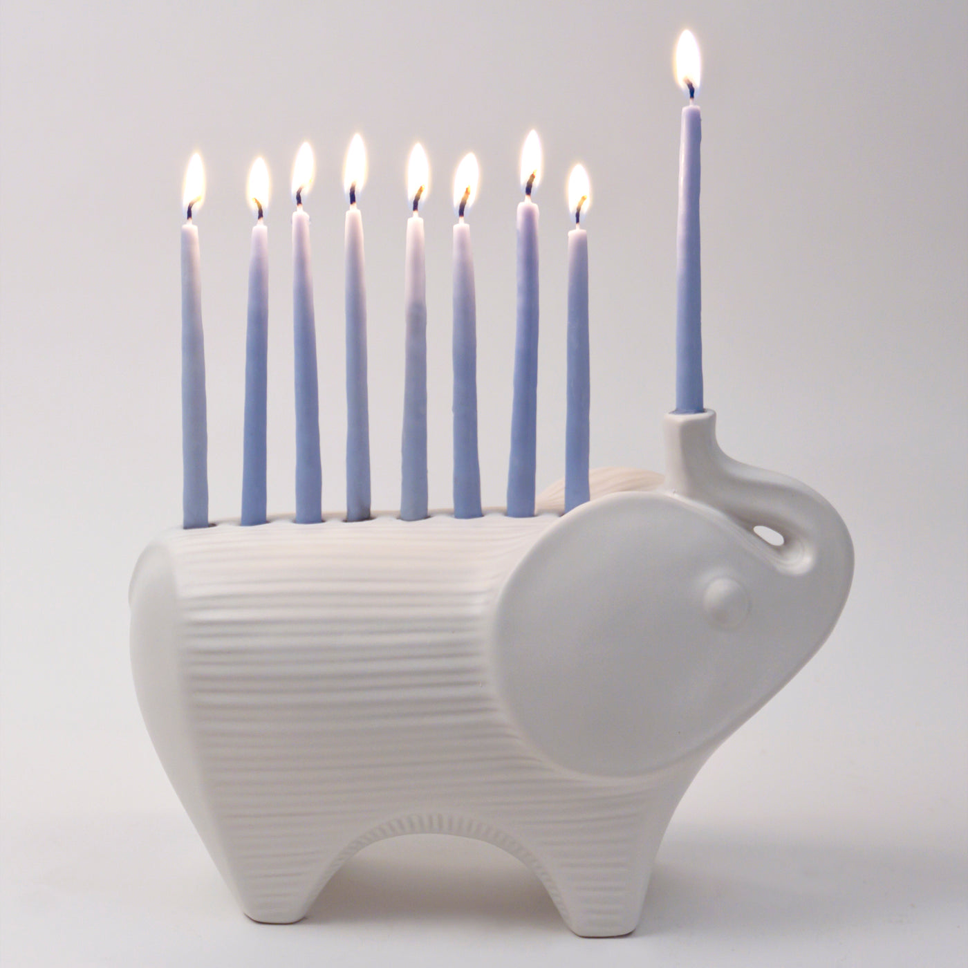 ceramic elephant menorah white with blue candles lit - angle view