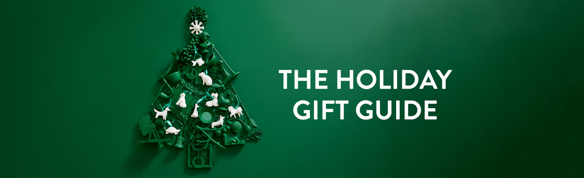 the holiday gift guide text over green tree made up of objects and white porcelain Jonathan adler ornaments on top 