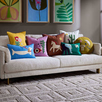Decorative pillows on a beige sofa with colorful artwork on the wall.
