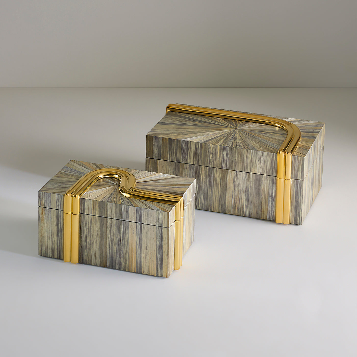 Two rectangular decorative boxes with striped beige, gray, and gold inlay and curved gold metal handles, photographed on a clean light gray studio background.