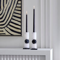 set of two geometric black and white candle stick holders styled with lit black candlesticks (not included) on a mantel next to abstract art 