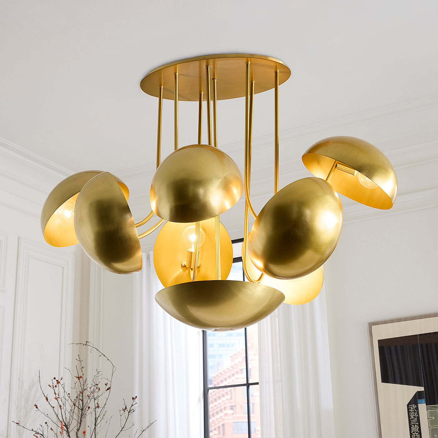 A modern gold ceiling light fixture with multiple dome-shaped metallic shades hanging from a round ceiling canopy in a bright white room.