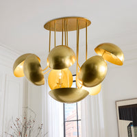 A modern gold ceiling light fixture with multiple dome-shaped metallic shades hanging from a round ceiling canopy in a bright white room.
