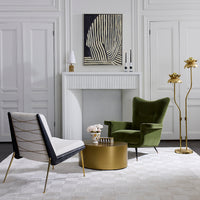 A styled interior scene with two lounge chairs, a round gold coffee table, a white fireplace, and decorative wall art in a bright, elegant room.