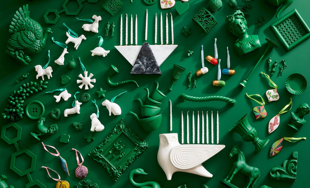 green background with assortment of green painted objects with pops of Jonathan Adler holiday ornaments and menorahs throughout  