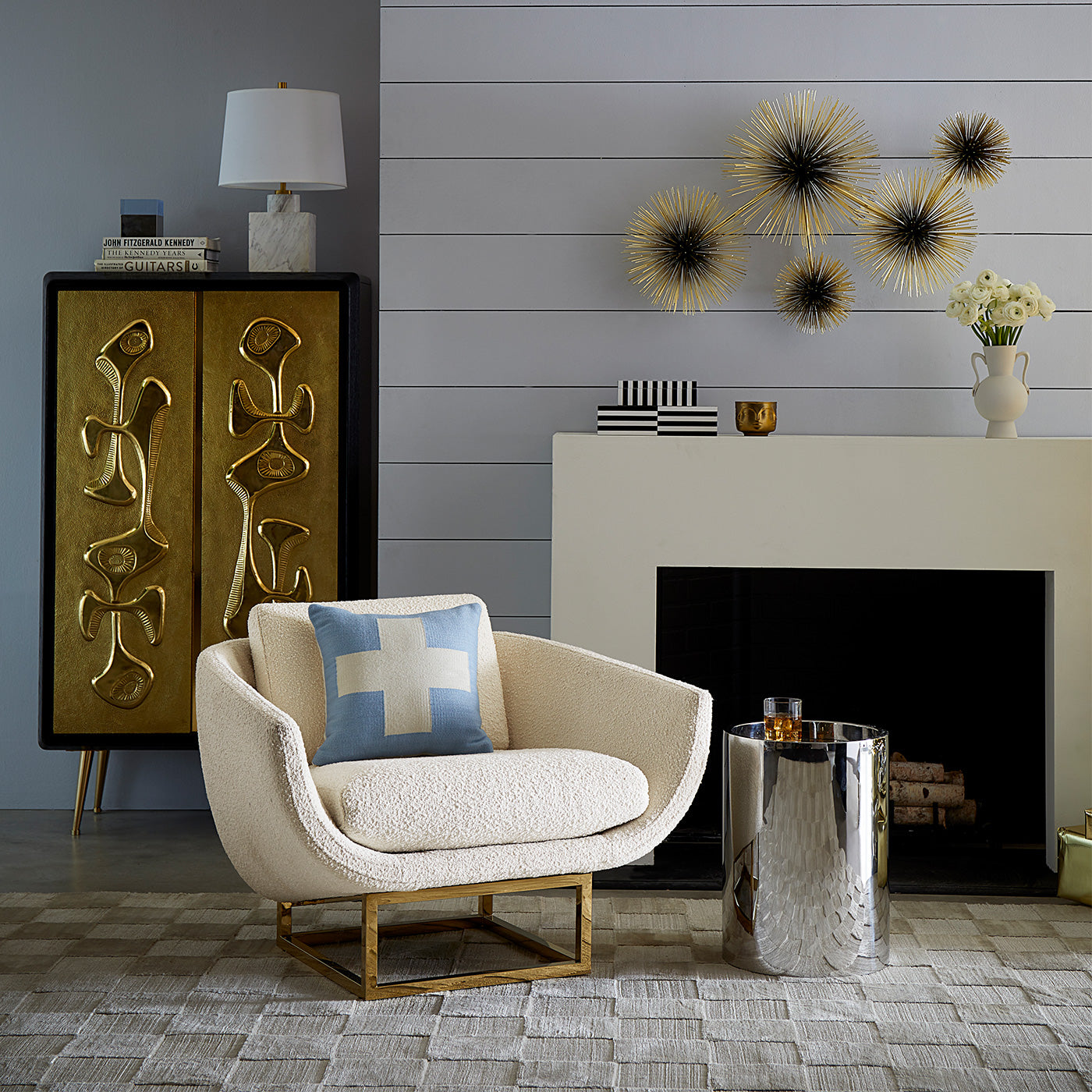 Modern living room with a beige armchair, decorative pillow, and a fireplace.
