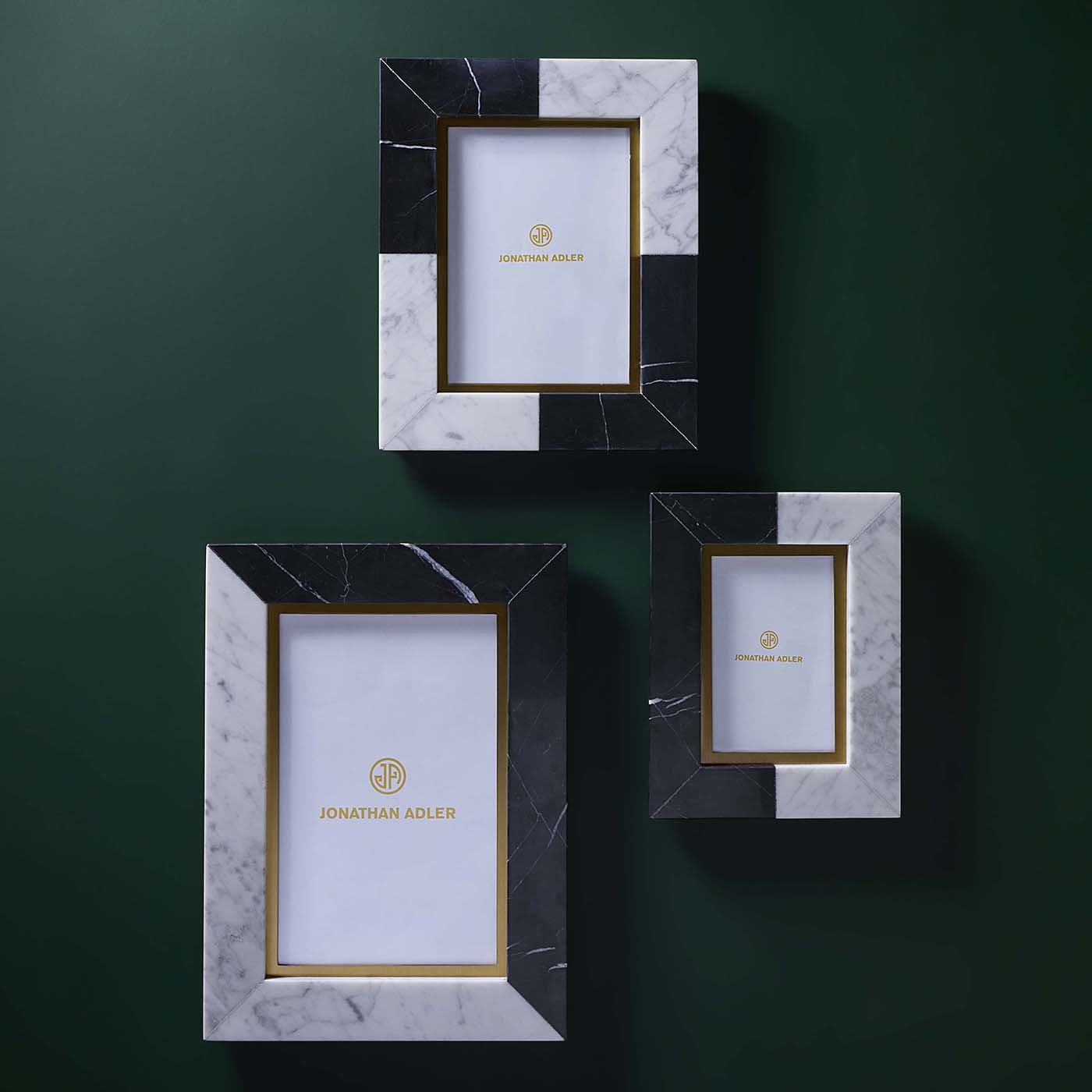 Three decorative picture frames with marble and black accents on a green background