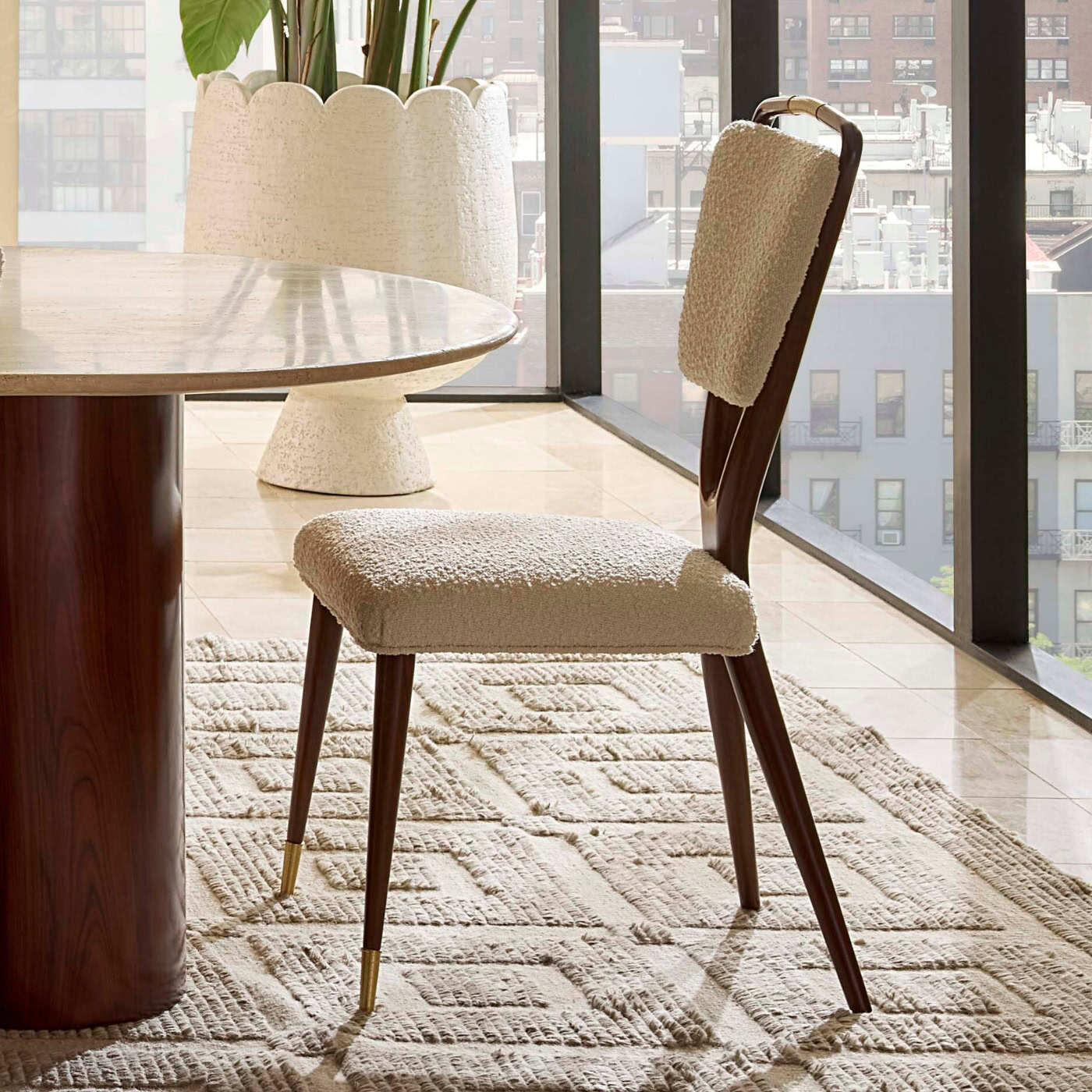Dining chair with textured cushion in a modern room with large windows.