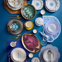 Assorted tableware including plates, bowls, and cutlery on a blue background
