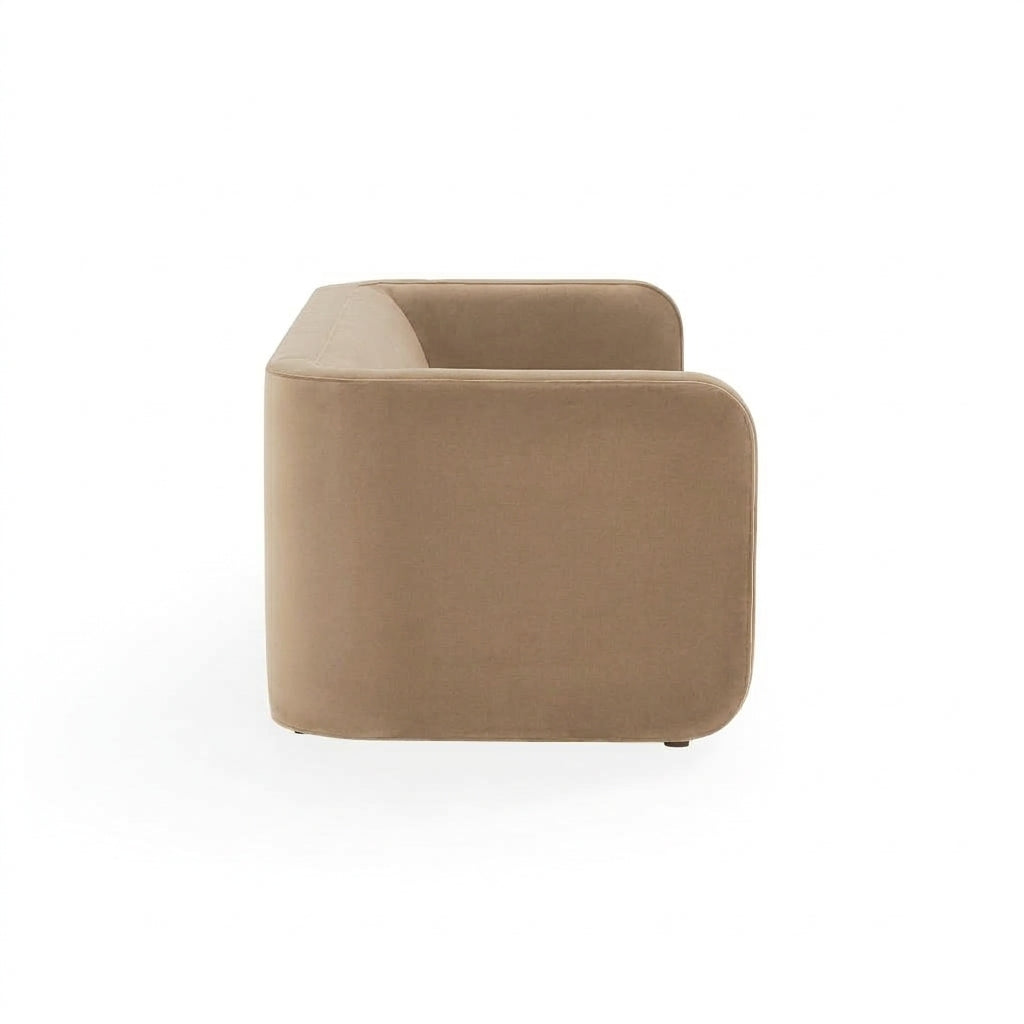 A modern low-profile armchair with a rounded rectangular silhouette, upholstered in a warm taupe fabric, shown from a three-quarters angle on a white background.