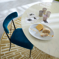 Round marble table with a plate of food and small containers, blue chair nearby.