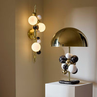 Modern wall sconce and table lamp with spherical design on a neutral background