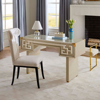 Beige desk with decorative elements in a room with large windows and a fireplace.