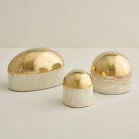 Three decorative items with gold and white finishes on a light background
