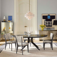 Dining room with a round black table and patterned chairs, featuring decorative elements like a mirror and artwork.