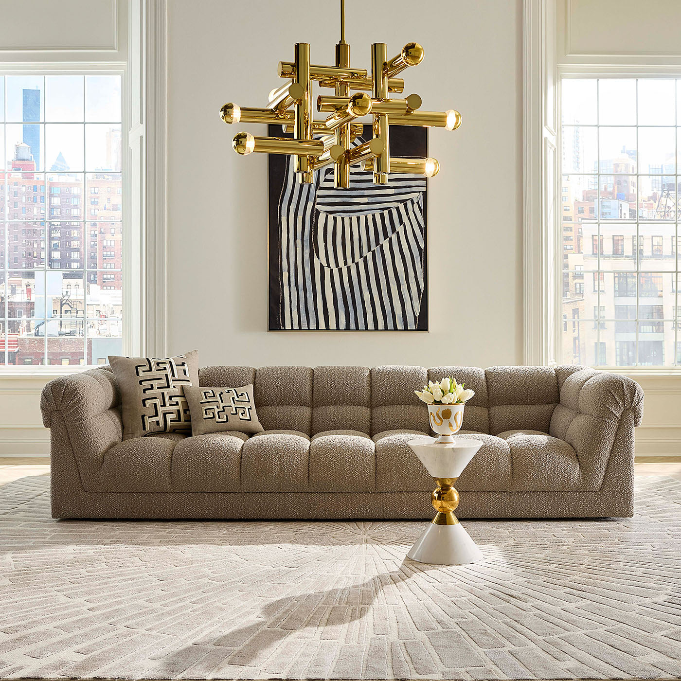 Modern living room with a beige sofa, gold chandelier, and abstract art.
