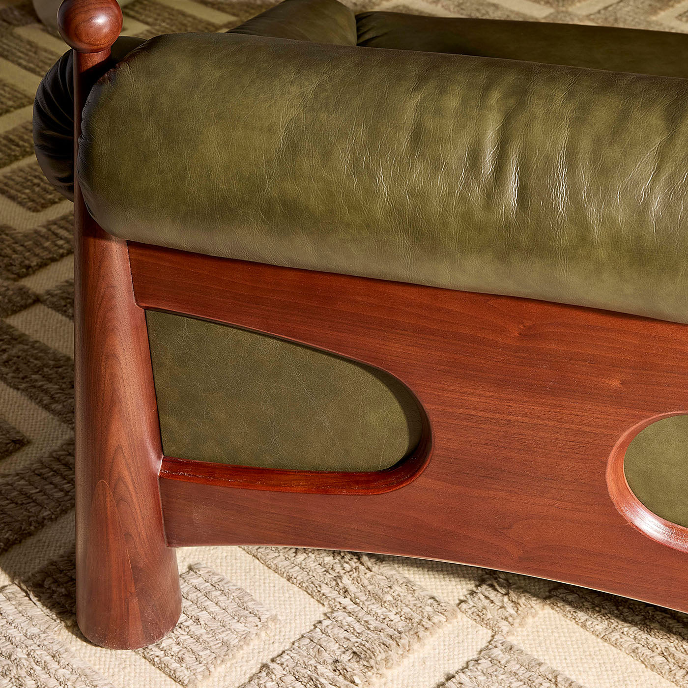 Green cushioned chair with wooden frame on a textured floor
