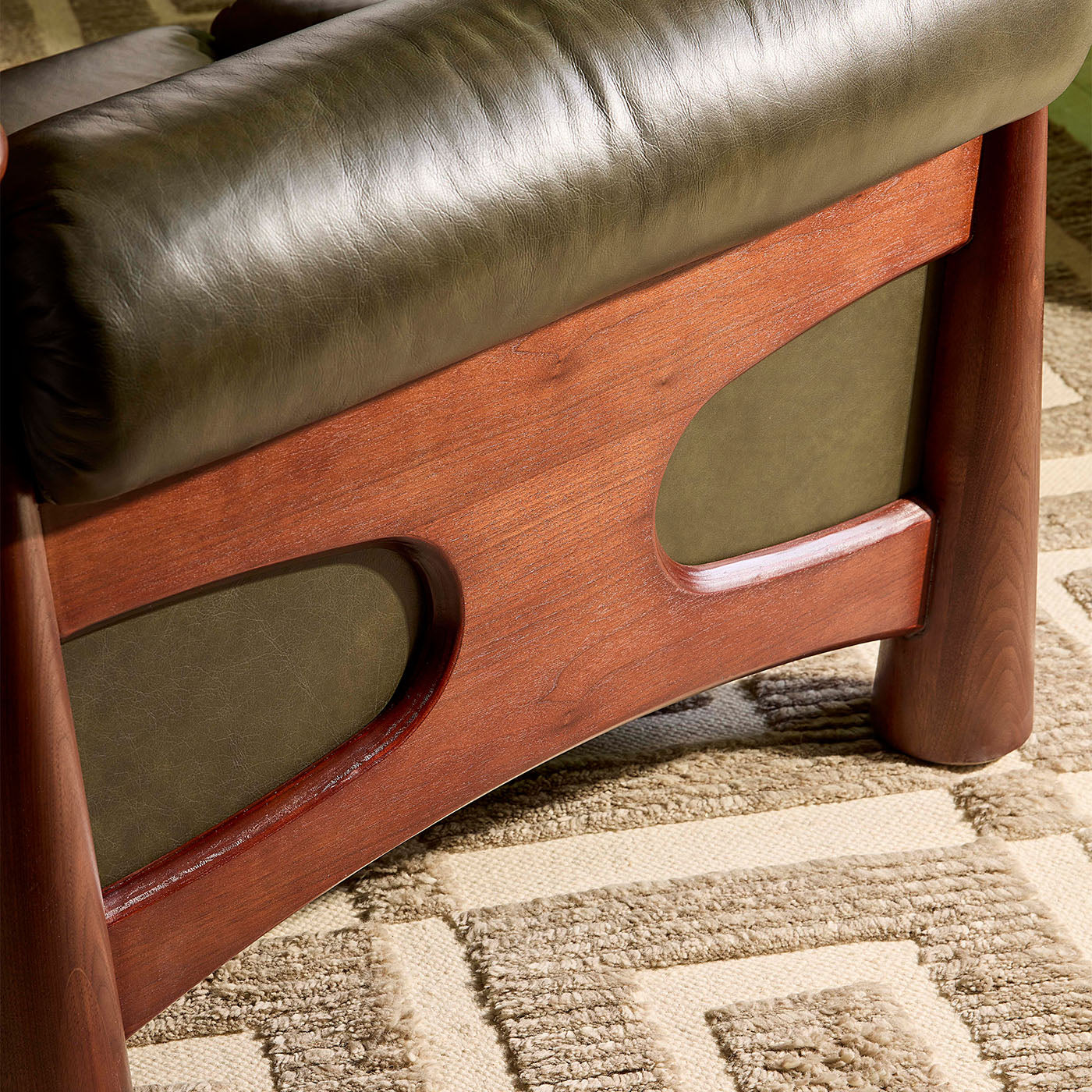 Close-up of a wooden and leather chair on a patterned carpet