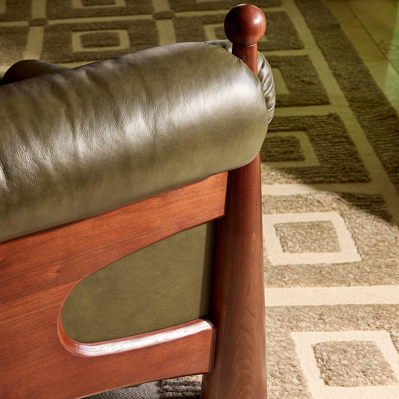 Close-up of a chair with leather seat and wooden frame on a patterned carpet
