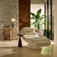 Modern living room with white lounge chairs, wooden side table, and decorative elements.