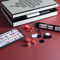 Mahjong game set with tiles and dice on a red surface