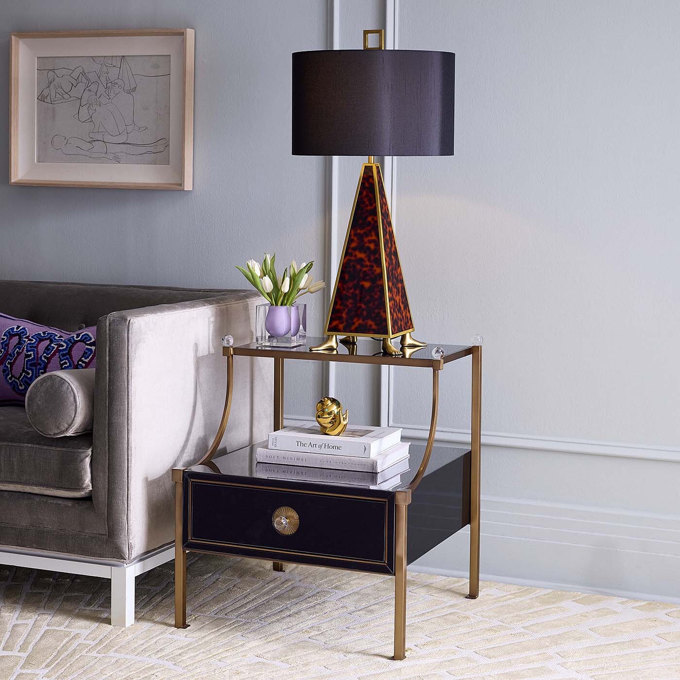 Decorative table with a lamp, books, and small plant in a living room setting.