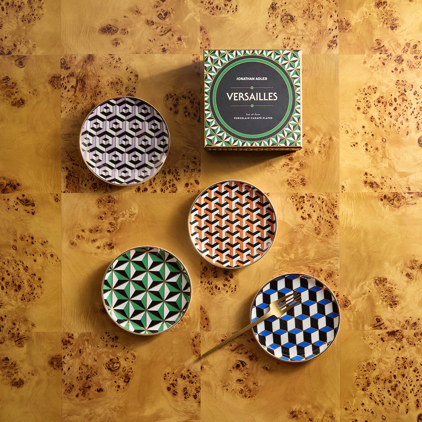 Four patterned plates with a box labeled 'Versailles' on a textured surface.