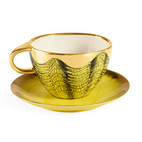 Gold and black patterned teacup and saucer on a white background