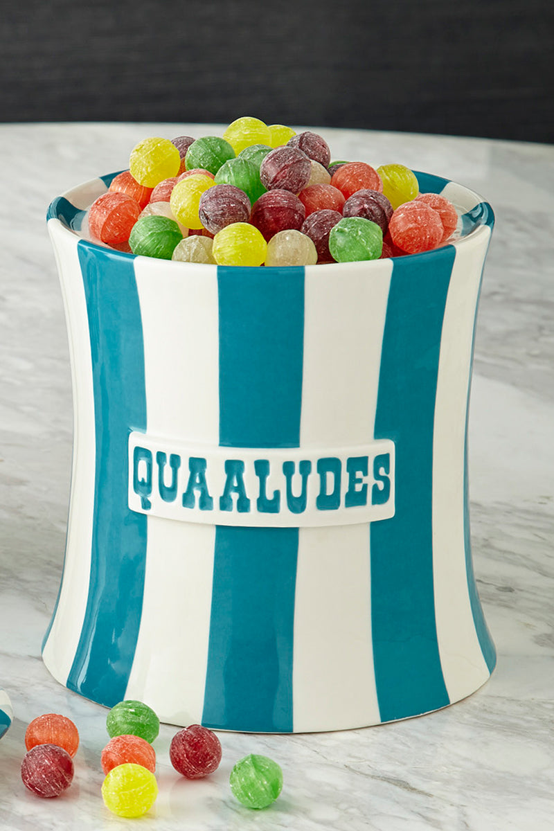 Turquoise and white striped canisters with cheeky phrase quaaludes written across filled with candies 