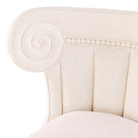 Close-up of a cream-colored upholstered chair with decorative nailhead trim on a white background