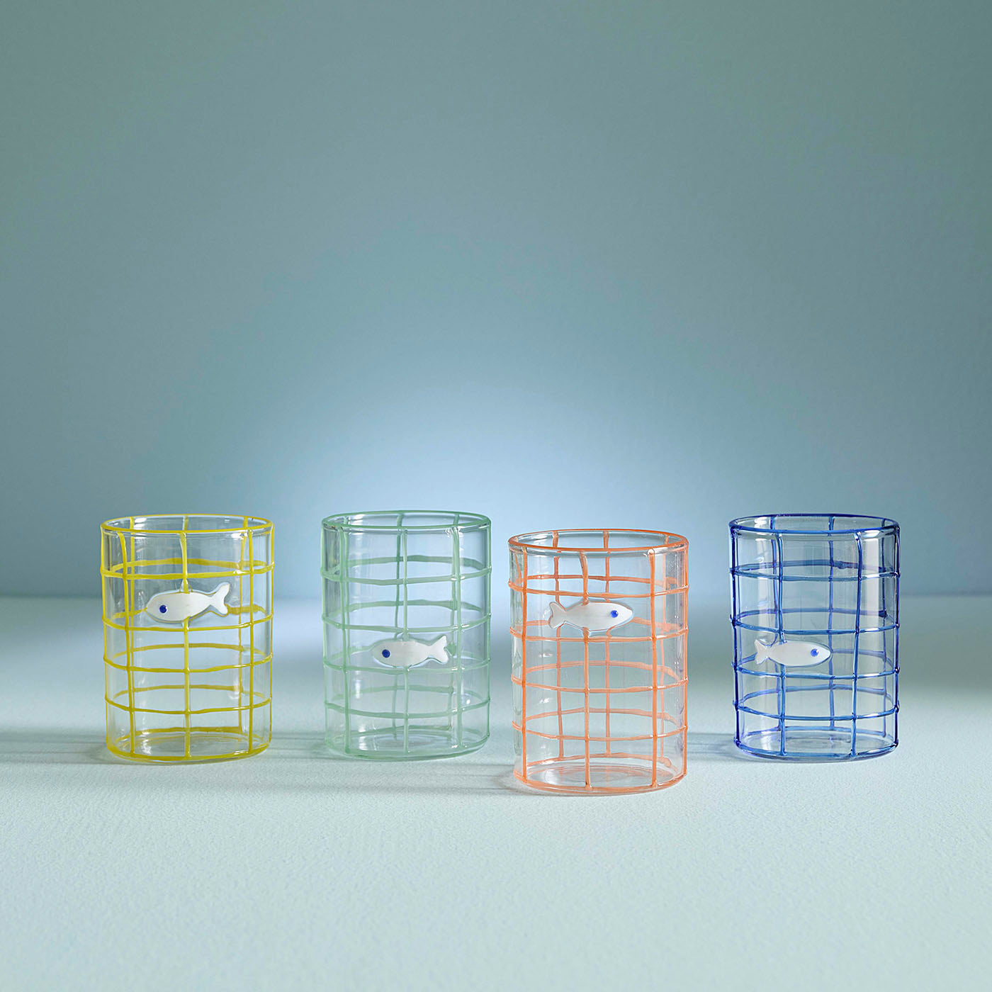 Four colorful glass tumblers with wireframe designs on a light blue background