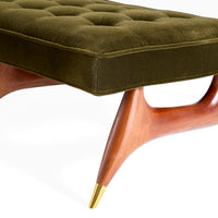 Green upholstered ottoman with wooden legs on a white background