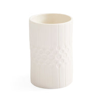 A white ceramic cup with a textured vertical ribbed pattern and a central honeycomb-like circular design, shown on a plain white background.