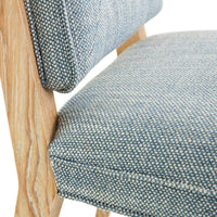Close-up of a chair with blue patterned fabric seat and wooden frame.