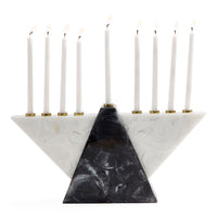 A three-tiered triangular Hanukkah menorah made of white and black marbled stone, holding nine white candles with gold-tone holders, set against a solid white background.
