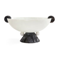 A sculptural bowl with a matte white interior and a dark, textured black exterior, featuring spherical side handles and a pedestal base on a white background.