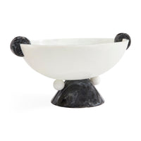 A modern sculptural bowl with a smooth matte white interior and a dark marbled black exterior, featuring spherical side handles and a pedestal base on a white background.