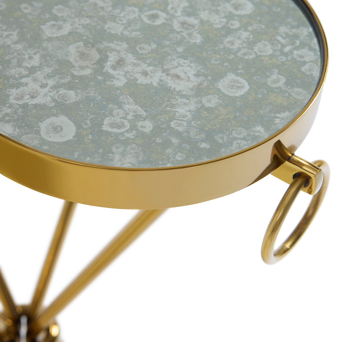 Close-up of a round side table with a distressed gray-green marble-patterned top and a polished gold metal frame and tripod base, featuring a side ring handle.