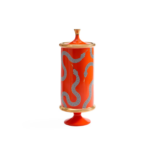 A tall cylindrical ceramic lidded jar or candle holder in bright orange-red, decorated with wavy dotted silver-gray patterns and accented with gold-toned trim at the top, bottom, and base.