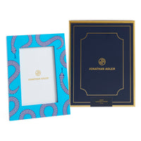 Two Jonathan Adler picture frames, one blue with a snake pattern and the other navy with gold text, on a white background.