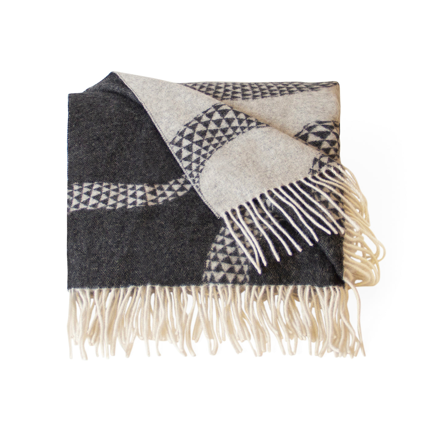A folded woven throw blanket with cream fringe, featuring a geometric pattern in black, gray, and cream on a white background.