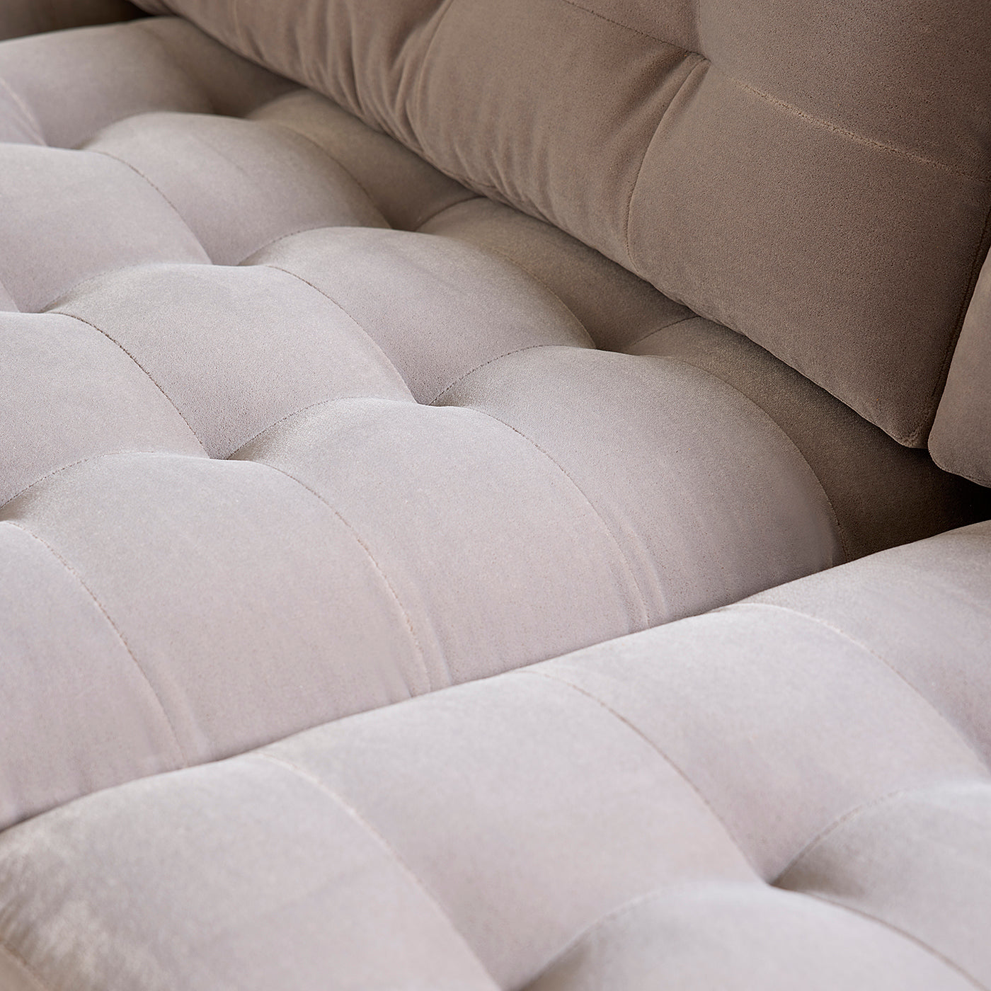 Close-up of a beige upholstered sofa with tufted design