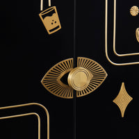 Close-up of a black cabinet door with ornate gold hardware, including a central sunburst eye-shaped pull handle and matching gold decorative accents.