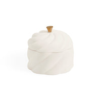 A white ceramic lidded container with a sculpted, ribbed surface and a small metallic gold knob on top, shown against a plain white background.