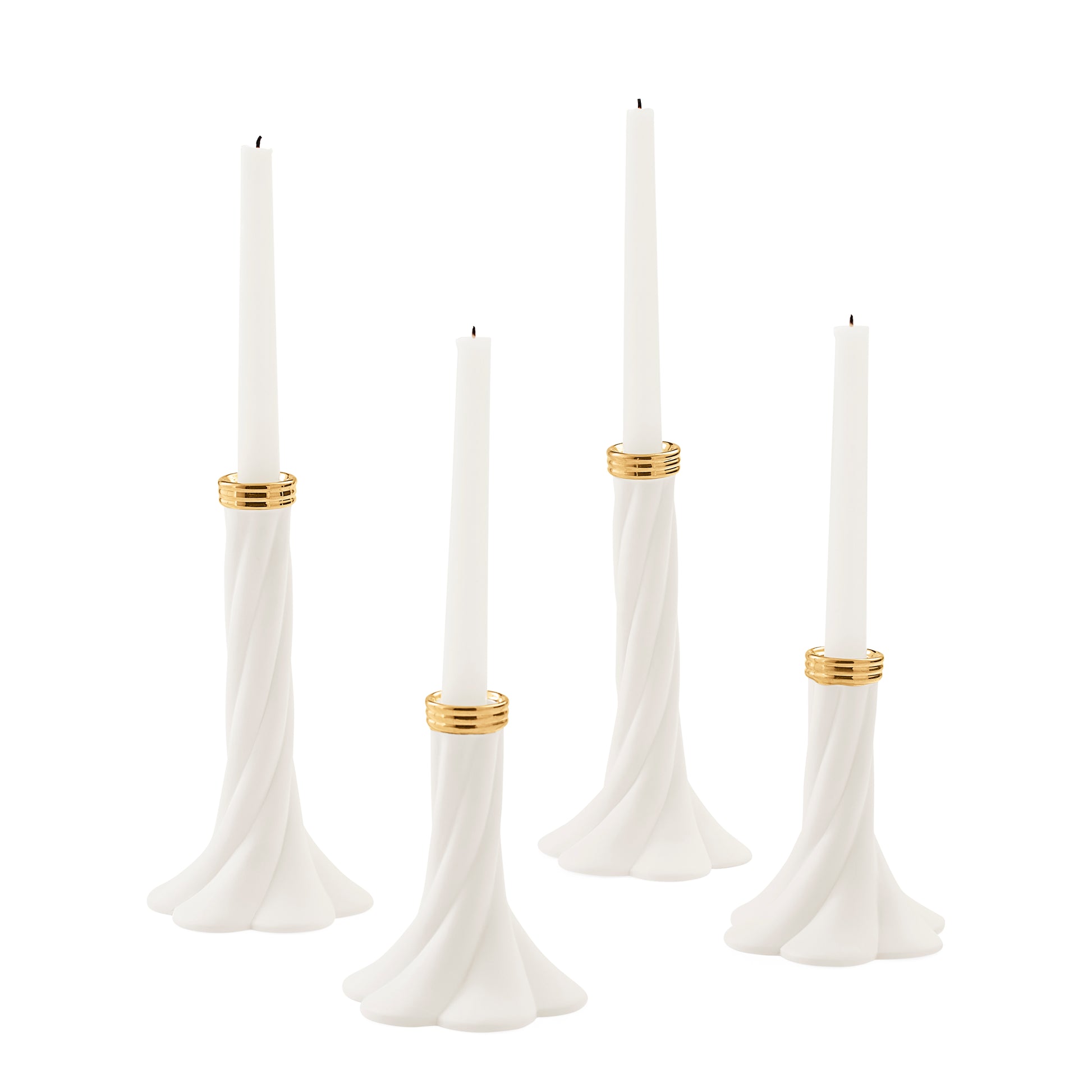 Four white taper candles in sculpted white holders with gold bands, shown on a plain white background.