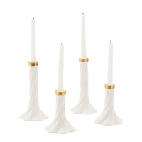 Four white taper candles in sculpted white holders with gold bands, shown on a plain white background.
