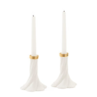 A pair of white taper candle holders with a flared, sculptural base and gold metallic bands near the top, shown on a plain white background.