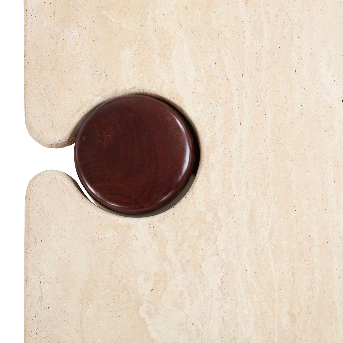 A close-up of a round, dark reddish-brown wooden knob or handle set into a light beige stone or travertine wall.